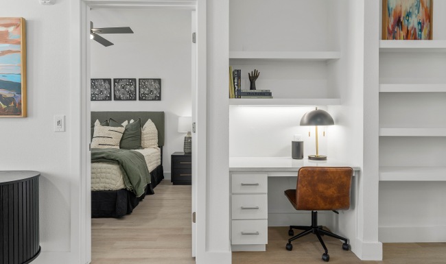 Apartment living room with built-in desk looking into bedroom